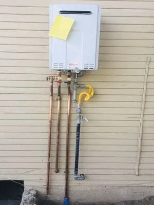 Tankless water heater mounted on wall with copper lines and gas connection