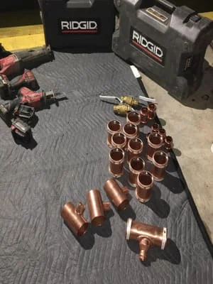 Copper plumbing fittings, tees, elbows, and couplings arranged with RIDGID professional tools