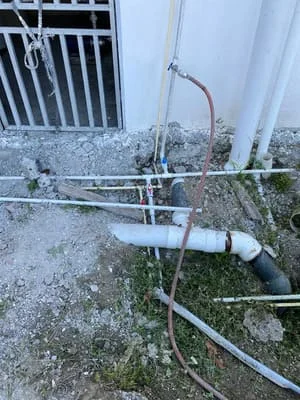 PVC plumbing lines with brackets and connections installed along concrete foundation