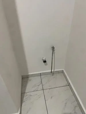 Marble tile shower floor with chrome plumbing fixtures and supply lines installed