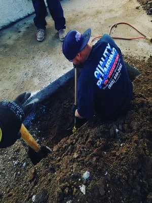 Technician installing large diameter underground drainage pipe in excavated soil trench