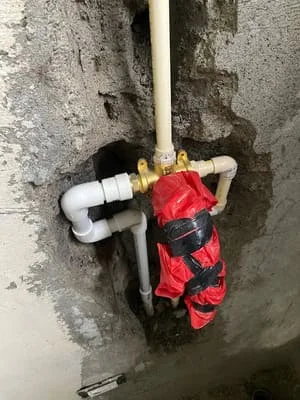 PVC pipes with brass ball valve and white coupling connections installed on concrete wall