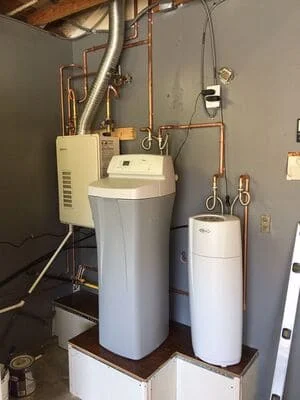 Dual water softener tanks with copper piping, control valves, and brine tank installation