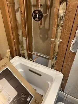 New white porcelain sink with chrome faucet installed in bathroom with framed walls and plumbing rough-in