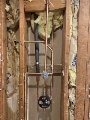 Copper supply lines and drain pipes installed in wall framing with electrical box